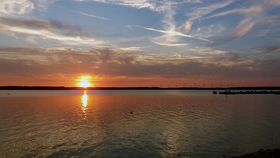 Die am Horizont untergehende Sonne färbt den Himmel und den See orange. © NDR Foto: Andreas Göllner aus Parchim