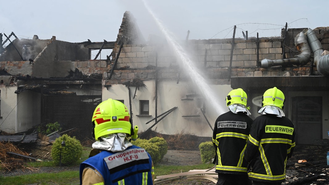 Feuerwehrleute richten in Sellin/Rügen einen Wasserstrahl auf das bereits abgebrannte Dach einer Pension.