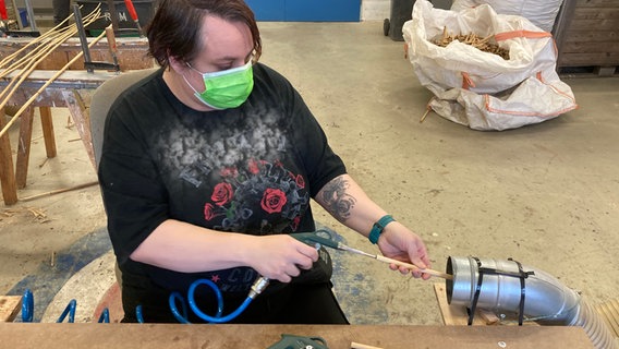 Frau arbeitet mit Maske in Werkstatt.  