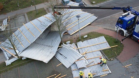 Mitarbeiter des Technischen Hilfswerks räumen auf einer Straße in Stralsund das abgedeckte Dach eines Supermarkts weg. © dpa-Bildfunk Foto: Stefan Sauer