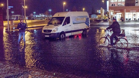 Ein Transporter steht auf einem von der Sturmflut leicht überschwemmten Parkplatz am Stadthafen. © dpa-Bildfunk 