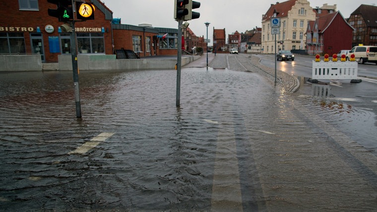 Wismar: Wegen Hochwasser ist eine teilweise überflutete Straßen am Hafen gesperrt. © dpa-Bildfunk Foto: Jens Büttner