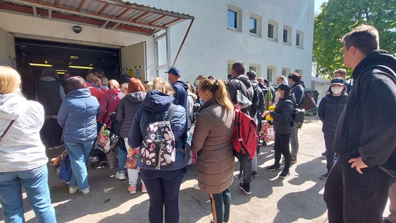 Menschen stehen an der Ausgabestelle der Rostocker Tafel an.  Foto: Dennis Mollenhauer