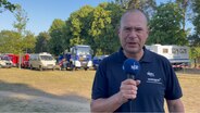 NDR Reporter vor Feuerwehr- und THW-Fahrzeugen © NDR 