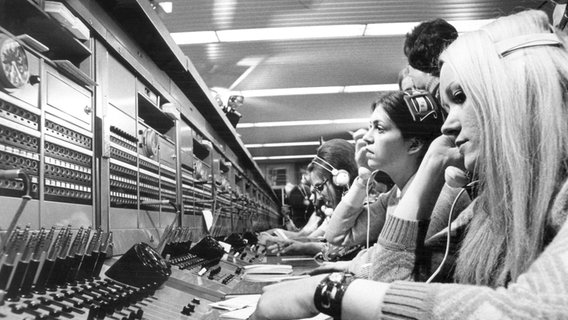 Archivbild einer Telefonzentrale in Westberlin im Januar 1971: Mehrere Frauen sitzen mit Telefonhörern vor großen Schaltschränken mit Wählscheiben  Foto: picture-alliance/ dpa | Konrad Giehr