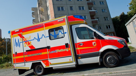 Ein Rettungswagen mit der Aufschrift "Telenotarzt" steht vor einem Hochhaus. © dpa-Bildfunk Foto: Stefan Sauer/dpa