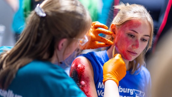 Eine junge Frau wird geschminkt, damit sie aussieht wie ein Unfall- oder Anschlagsopfer. © dpa Foto: Jens Büttner