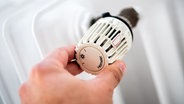 Eine Hand dreht an einem Heizunagsthermostat © dpa Foto: Hauke-Christian Dittrich