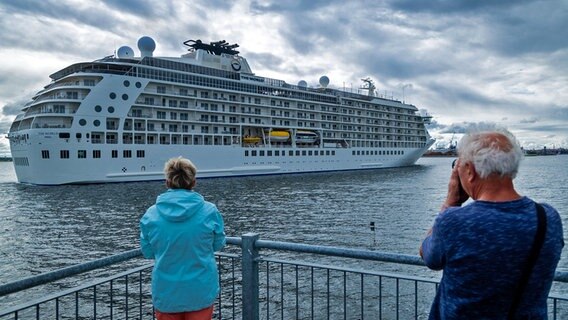 Passanten beobachten von der Seebrücke aus das Einlaufen des Luxusliners "The World" in den Wismarer Hafen. © dpa Foto: Jens Büttner