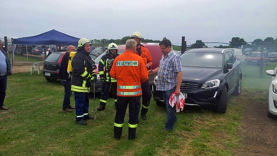 Leif Tennemann  zusammen mit Feuerwehrmännern vor seinem Auto. © NDR 