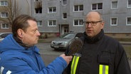 NDR MV Live Reporter Sven-Peter Martens und der Torgelower Wehrführer Lars Cornelius vor einem Haus mit einer ausgebrannten Wohnung. © NDR Foto: NDR