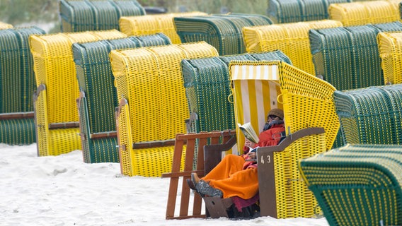 Eine Urlauberin sitzt lesend in einem Strandkorb im Seebad Binz auf der Insel Rügen. © dpa-Bildfunk Foto: picture alliance / dpa