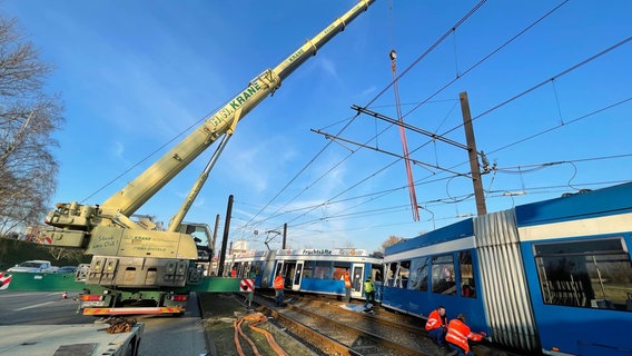 Ein Kran positioniert sich über einer der beiden Straßenbahnen, die bei einem Unfall in Rostock zerstört worden sind. © NDR.de Foto: Christian Kohlhof