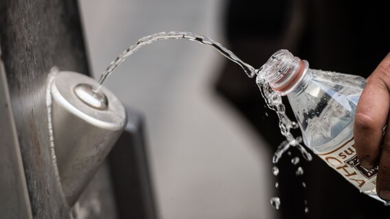 Ein Mann füllt sich an einem Brunnen kostenlos Trinkwasser in die eigene Flasche. © dpa Foto: Andreas Arnold