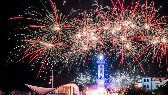 Am Himmel über dem Leuchtturm in Rostock-Warnemünde funkelt Feuerwerk. © dpa Bildfunk Foto: Frank Hormann