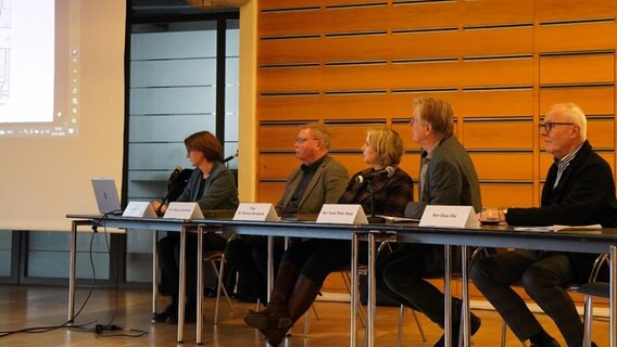 Fünf Männer und Frauen sitzen an einem Tisch und schauen dabei auf ein Leinwand. © NDR Foto: Christoph Woest