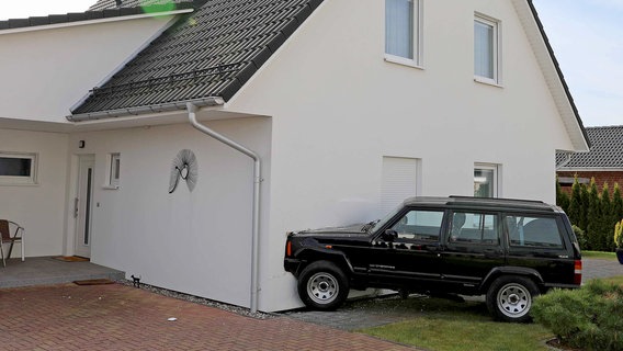 Ein schwarzer Geländewagen steckt mit der Motorhaube in der Fassade eines weißen Einfamilienhauses. © Stefan Tretropp Foto: Stefan Tretropp