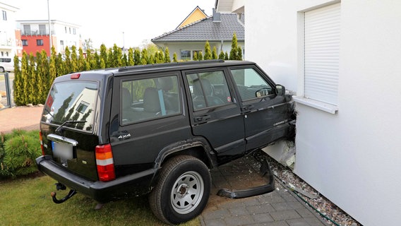 Ein schwarzer Geländewagen steckt mit der Motorhaube in der Fassade eines weißen Einfamilienhauses. © Stefan Tretropp Foto: Stefan Tretropp