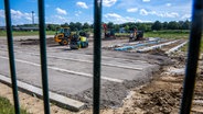 Eine Baufirma bereitet hinter einem Metallzaun die Fundamente für das Aufstellen von Wohncontainern für eine Flüchtlingsunterkunft im Gewerbegebiet von Upahl vor. © dpa Bildfunk Foto: Jens Büttner