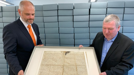 Stralsunds Oberbürgermeister Alexander Badrow und Stadtarchivar Dirk Schleinert halten die Urkunde zum Stralsunder Frieden im Depot des Stadtarchives. © NDR Foto: Silvana Mundt