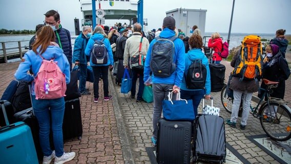 Urlauber mit Rucksäcken und Koffern warten im Hafen Schaprode auf Rügen auf das Fährschiff zur Überfahrt auf die Ostseeinsel Hiddensee. © dpa-Bildfunk Foto: Jens Büttner