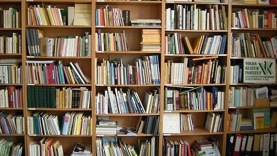 Bücherregale auf denen ein Schild des Volkskulturinstituts angebracht sind. © NDR 