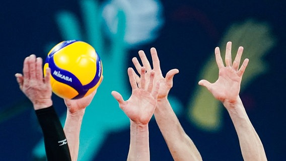 Hände strecken sich in die Luft und ein Volleyball fliegt hindurch © dpa Bildfunk Foto: Uwe Anspach
