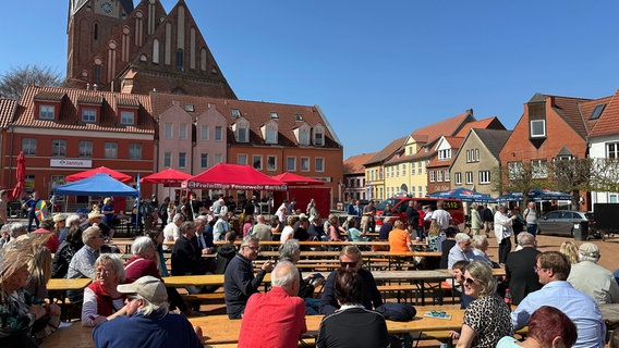 Menschen sitzen auf Bänken auf dem Barther Marktplatz. © NDR Foto: Mathias Marius Krüger