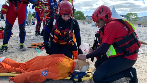 Zwei Rettungschwimmer mit Helmen und in Neoprenanzügen üben an einem Dummy. © DRK Wasserwacht 