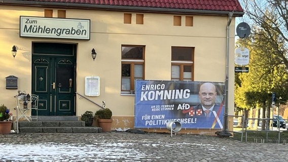 Neben dem Eingang einer Kneipe und einem Gemeindehaus steht ein großes Wahlplakat der AfD. Neben dem Eingang einer Kneipe und einem Gemeindehaus steht ein großes Wahlplakat der AfD. © NDR Foto: G. Hoffmann
