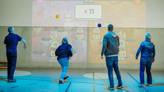 Mitarbeiter der Stadt Sassnitz testen ein neues System in der Sporthalle, bei der 3D-Kameras ein interaktives Spielfeld an die Wand projizieren. © Stadt Sassnitz 