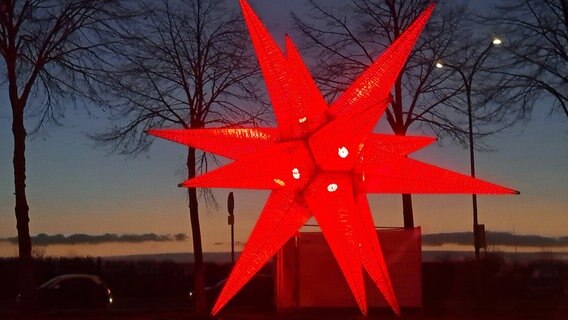Ein über 7 Meter hoher Stern leuchtet in der Farbe rot. Ein über 7 Meter hoher Stern leuchtet in der Farbe rot. © NDR Foto: Michaele Rüting