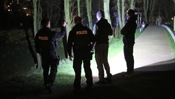 Einer Gruppe von Polizisten leuchtet mit Taschenlampen in die dunklen Wallanlagen in der Rocstocker Innenstadt. © NonStopNewsRostock Foto: Stefan Tretropp/ NonStopNewsRostock