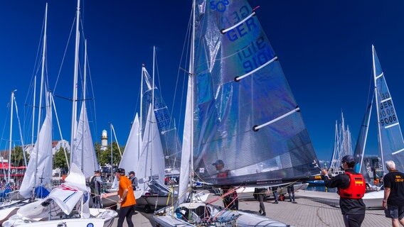 Segelsportler bereiten ihre Boote für eine Wettfahrt zum Auftakt Warnemünder Woche vor. © dpa-Bildfunk Foto: Jens Büttner/dpa