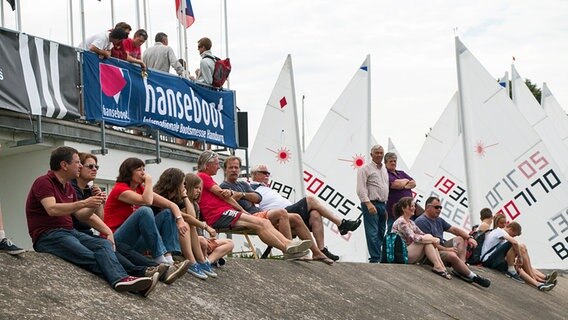 Segler sitzen am Strand und warten auf Wind. © warnemuender-woche.com Foto: Pepe Hartmann