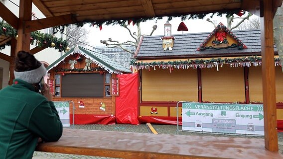 Neubrandenburg: Eine Schaustellerin telefoniert vor ihrem geschlossenen Stand auf dem Weihnachtsmarkt. © dpa-Bildfunk Foto: Bernd Wüstneck
