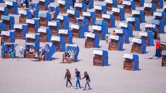 Urlauber gehen über den Strand an der Ostseeküste in Warnemünde. © dpa 