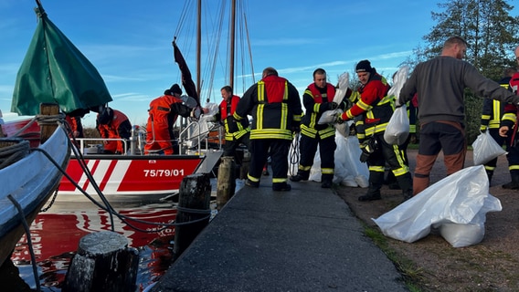 Die Feuerwehr befüllt Boote mit Sandsäcken am Hafen in Wieck. © NDR Foto: Anna-Lou Beckmann