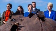 Annalena Baerbock (M, Bündnis 90/Die Grünen), Bundesaußenministerin, steht im Hafen von Wismar beim Treffen des Ostseerats mit Thordis Kolbrun Reykfjörd Gylfadottir (l), Außenministerin von Island, Johanna Sumuvuori (2.v.l.), Staatssekretär beim Außenminister von Finnland, Gabrielius Landsbergis (2.v.r.), der litauische Außenminister, und Manuela Schwesig (SPD), der Ministerpräsidentin von Mecklenburg-Vorpommern, hinter Munitionsfunden aus der Ostsee. © dpa-Bildfunk Foto: Jens Büttner