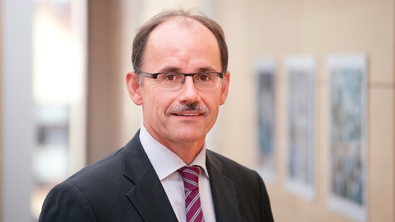 Der zum zweiten Mal wiedergewählte Präsident der IHK Neubrandenburg, Thomas Blank. Er trägt eine Brille, einen Schnauzer und einen Anzug mit weißem Hemd und roter Krawatte. © IHK / Thomas Kunsch Foto: IHK / Thomas Kunsch