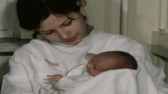 Eine Frau hält in einer Klinik in der DDR ein neugeborenes Kind im Arm. © NDR Nordmagazin 