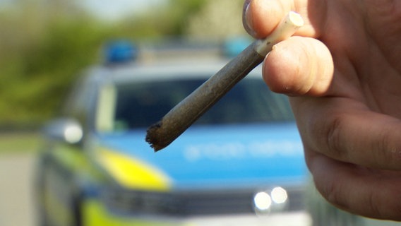 Ein Joint qualmt vor einem Polizeiauto. © NDR 