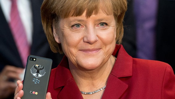 Bundeskanzlerin Angela Merkel steht mit einem abhörsicheren Blackberry am Stand von Secusmart beim Eröffnungsrundgang auf der CeBIT in Hannover. © dpa Foto: Julian Stratenschulte