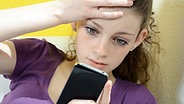 Teenagerin schaut entsetzt auf ihr Smartphone © Fotolia.com Foto: gemphotography