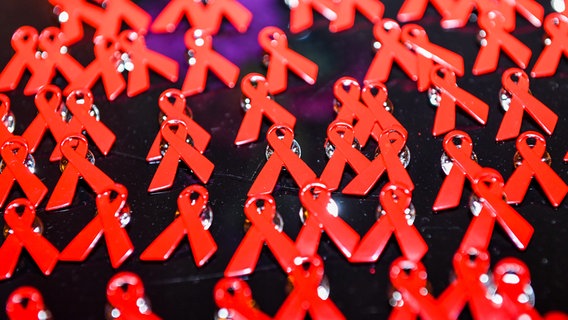 Aids-Schleifen liegen als Anstecknadeln auf einem Tisch. © picture alliance/dpa/dpa-Zentralbild | Jens Kalaene Foto: Jens Kalaene