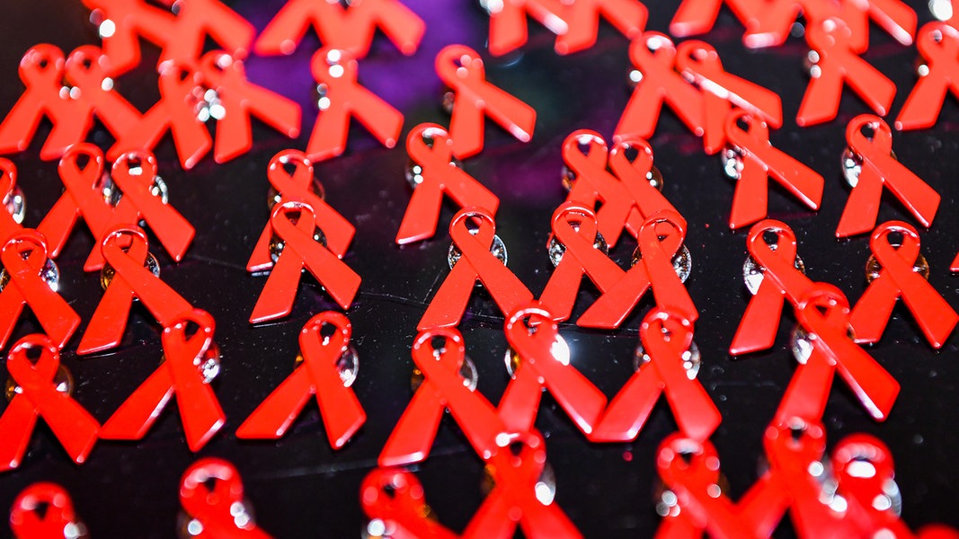Aids-Schleifen liegen als Anstecknadeln auf einem Tisch. 