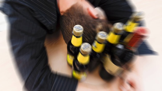 Ein betrunkener Jugendlicher liegt umringt von Bierflaschen mit dem Kopf auf einem Tisch. © picture alliance/blickwinkel/McPHOTO 