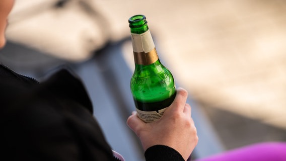 Eine Jugendliche hält vor ihrem Haus eine Flasche Bier in der Hand. © Silas Stein/dpa +++ dpa-Bildfunk +++ Foto: Silas Stein