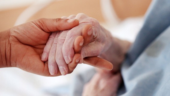 Eine junge Hand hält eine ältere. © picture alliance/dpa Foto: Oliver Berg