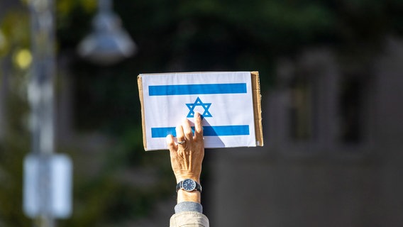 Ein Teilnehmer der Kundgebung "Aufstehen gegen Israelhass und Antisemitismus" hält ein Schild mit der israelischen Flagge in die Höhe. © picture alliance/dpa/Thomas Banneyer Foto: Thomas Banneyer